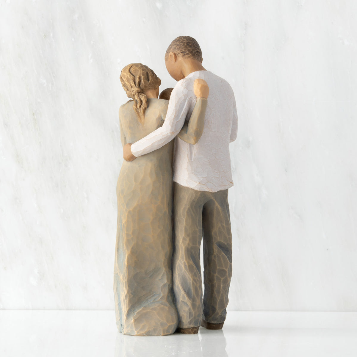 Back view of standing couple, woman has lighter skin and hair; man has darker skin and hair, holding a baby between them.