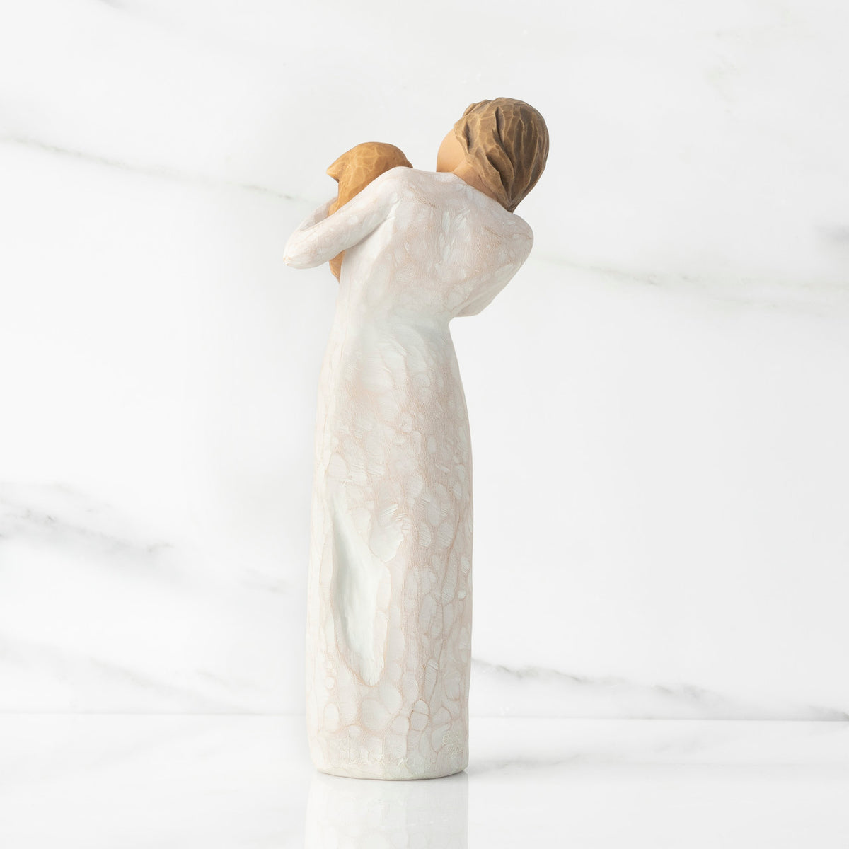 Back view, standing female figure in cream dress, holding golden color puppy in her arms