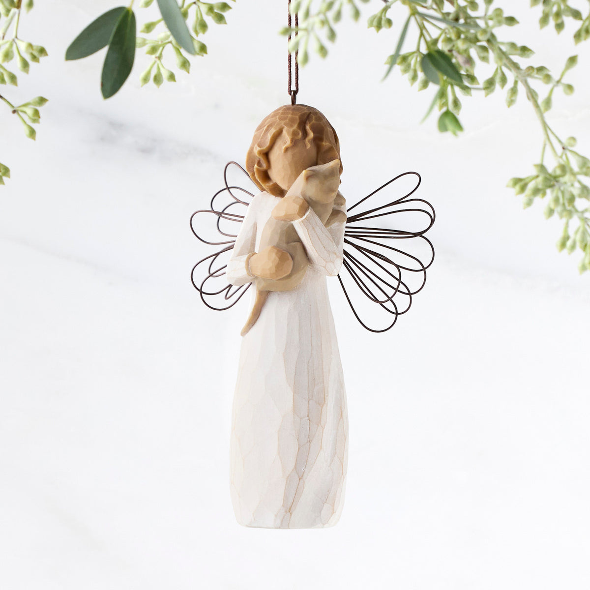 Figure in cream dress with wire wings, holding gray cat in arms, ornament loop attached to head