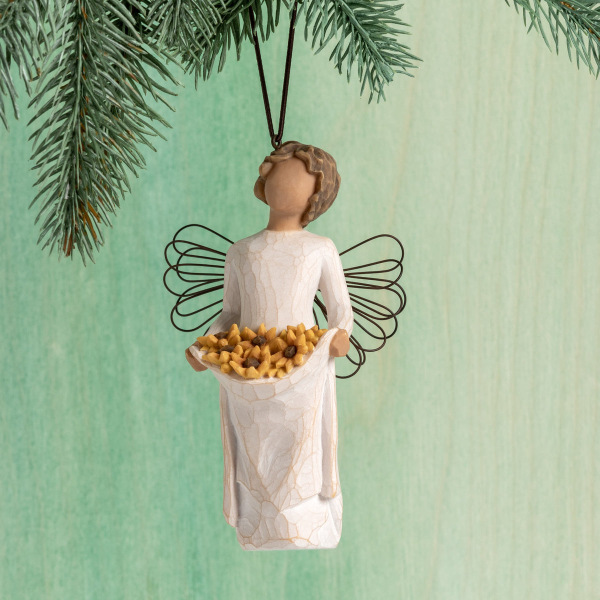 Front view: female figure with wire wings, holding skirt filled with yellow sunflowers; hook and loop affixed to head