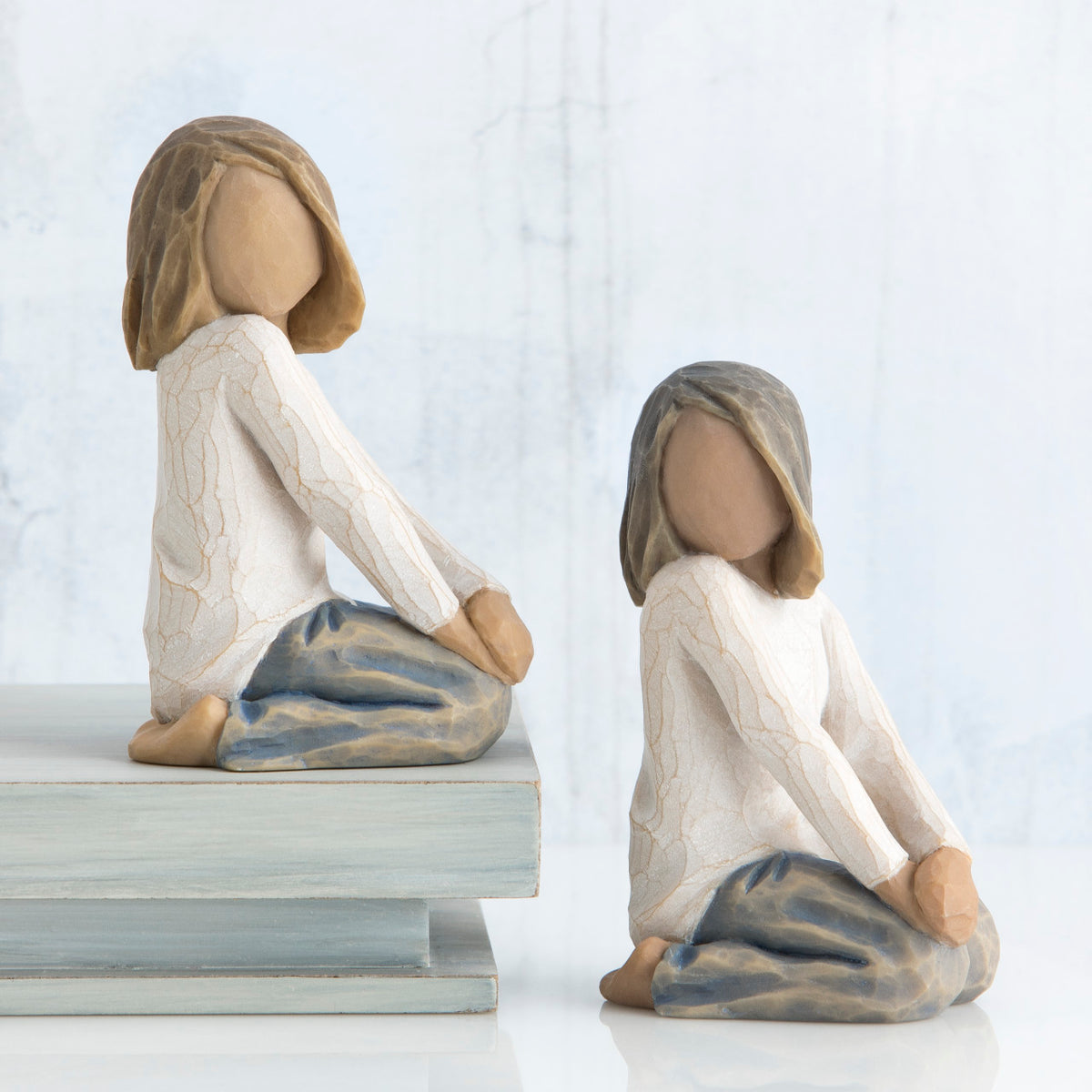 Set of two young girl figurines kneeling in white shirts and blue bottoms