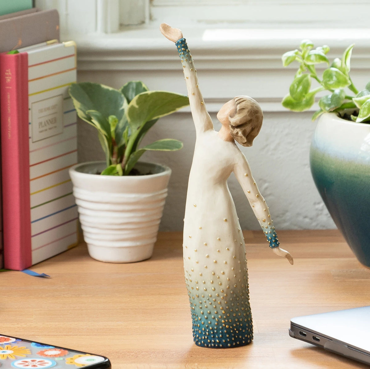 Willow Tree Shine, 8" hand-painted standing resin figure in cream and blue ombré dress with gold-leaf dots, looking up, one arm extended upward, on desk