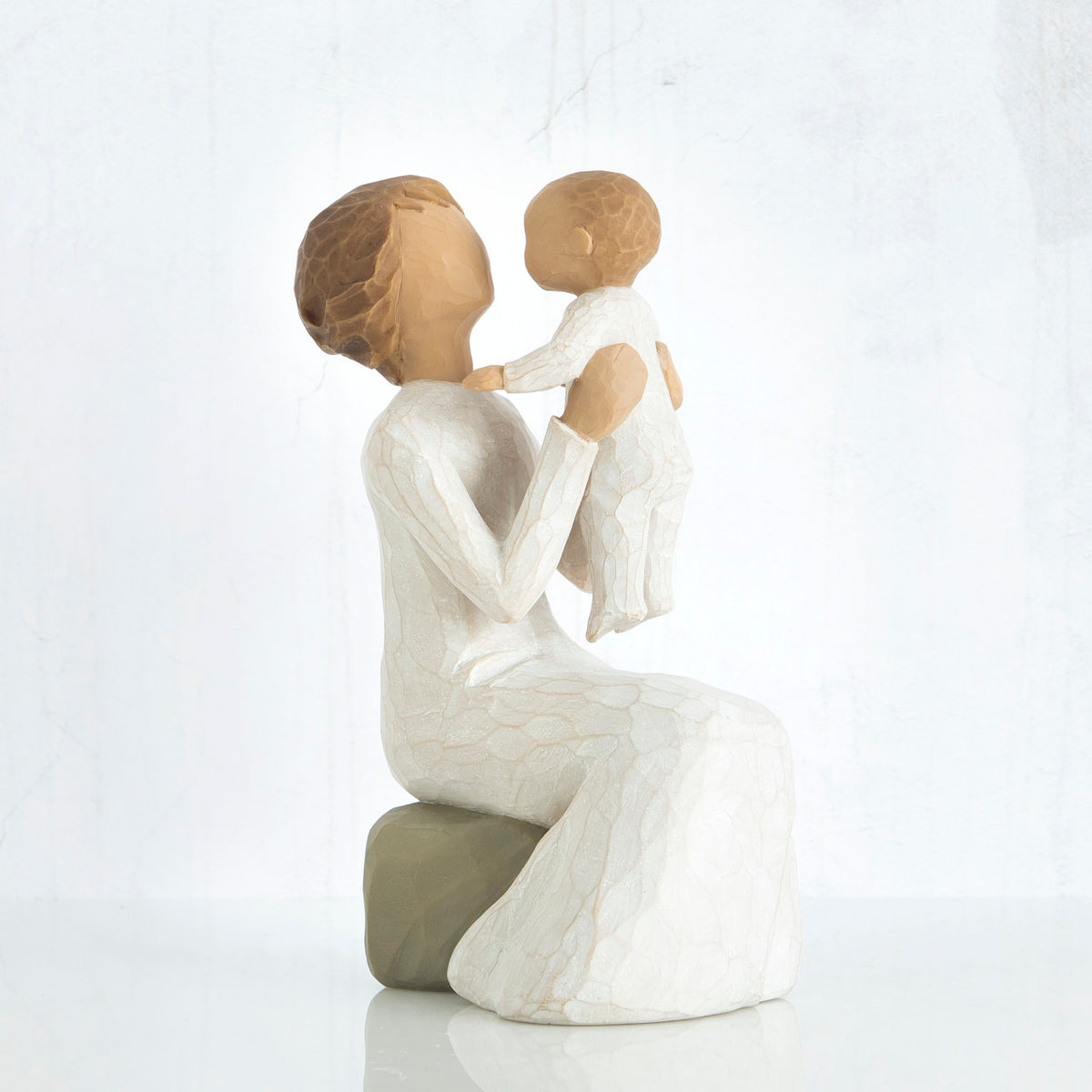 Mother figurine holding baby in her lap - both faceless, wearing white