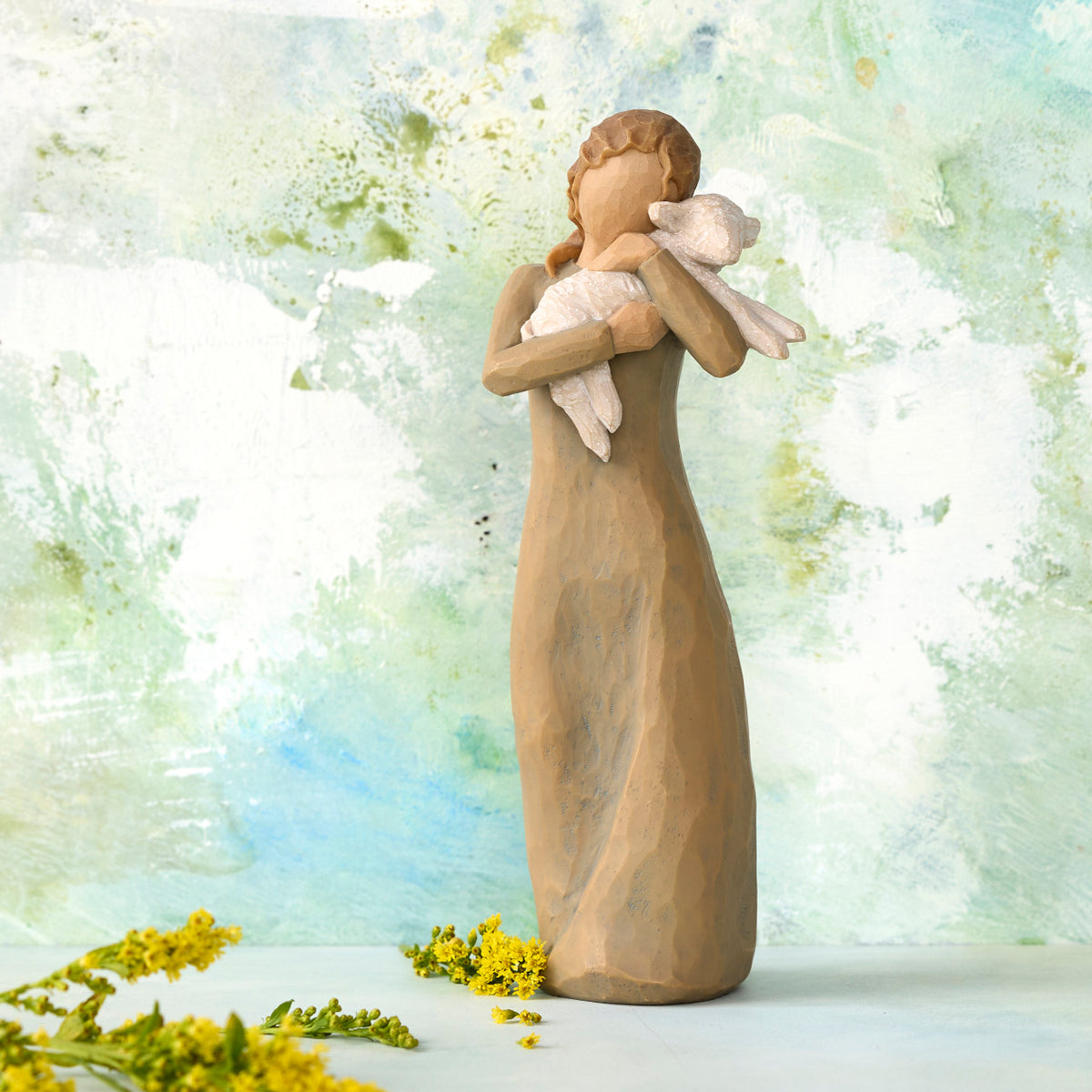 Willow Tree Peace on Earth, 8.5”h hand-painted standing resin figure in gray-green dress, holding baby lamb, in front of green-white painting