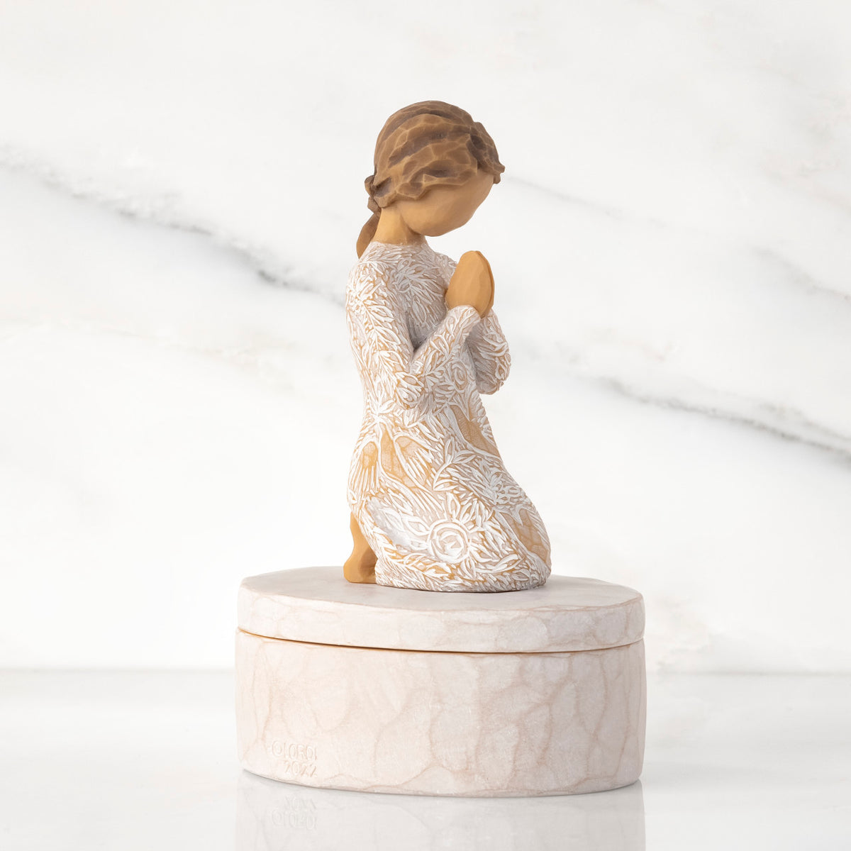 Right side: cream oval resin box, 3-D figure in prayer pose atop lid, in cream dress carved with birds and flowers