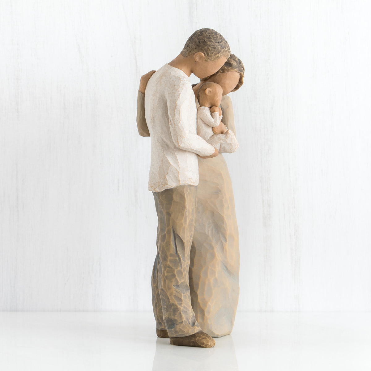 Side view of mother and father figurines holding a baby in their arms