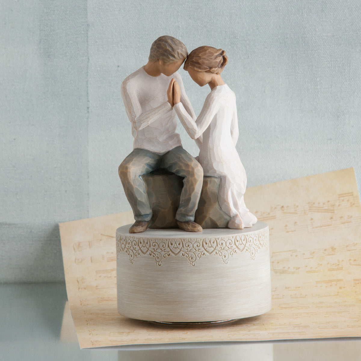 Man and woman figurines holding hands on cream raised rock pendant