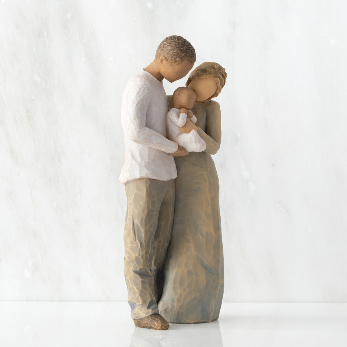 Right view of standing couple, woman has lighter skin and hair; man has darker skin and hair, holding a baby between them.