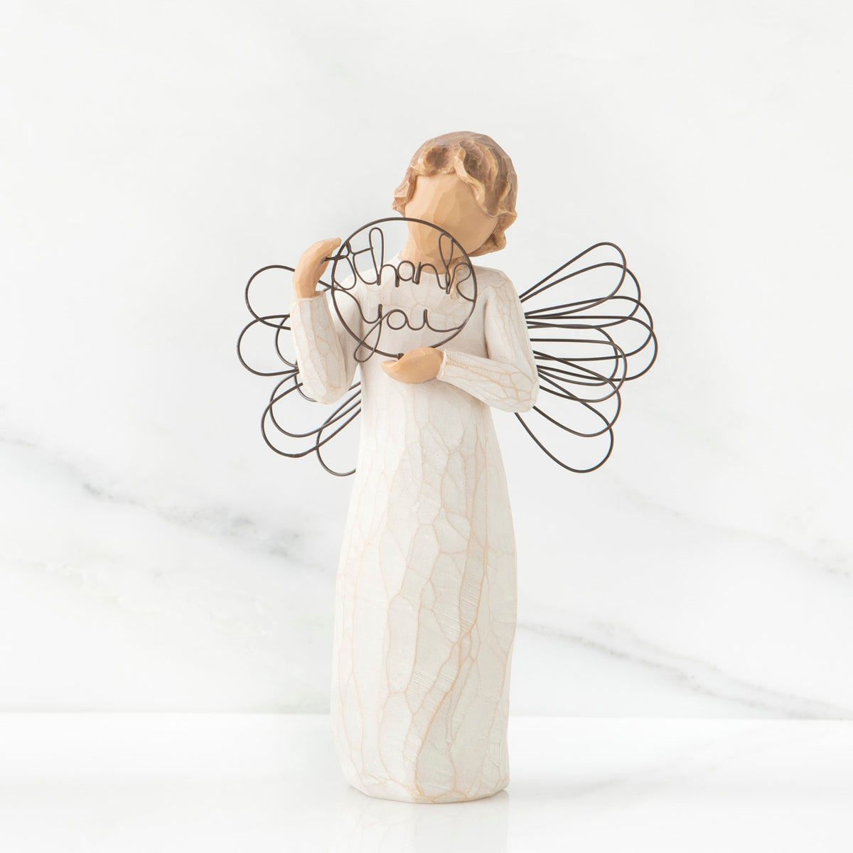 Front view of angel with tied back brown hair, holding up a circular wire sign that says "thank you"