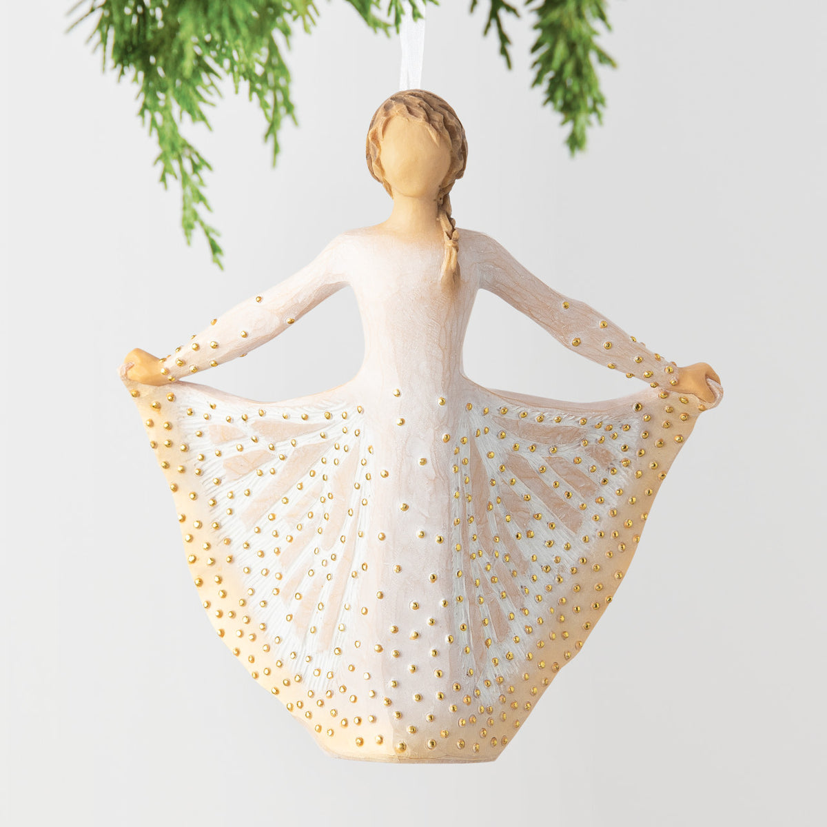 Front view, figure in cream dress, holds skirt with both hands, carved like monarch, dotted with gold. Hook, loop on ornament's head
