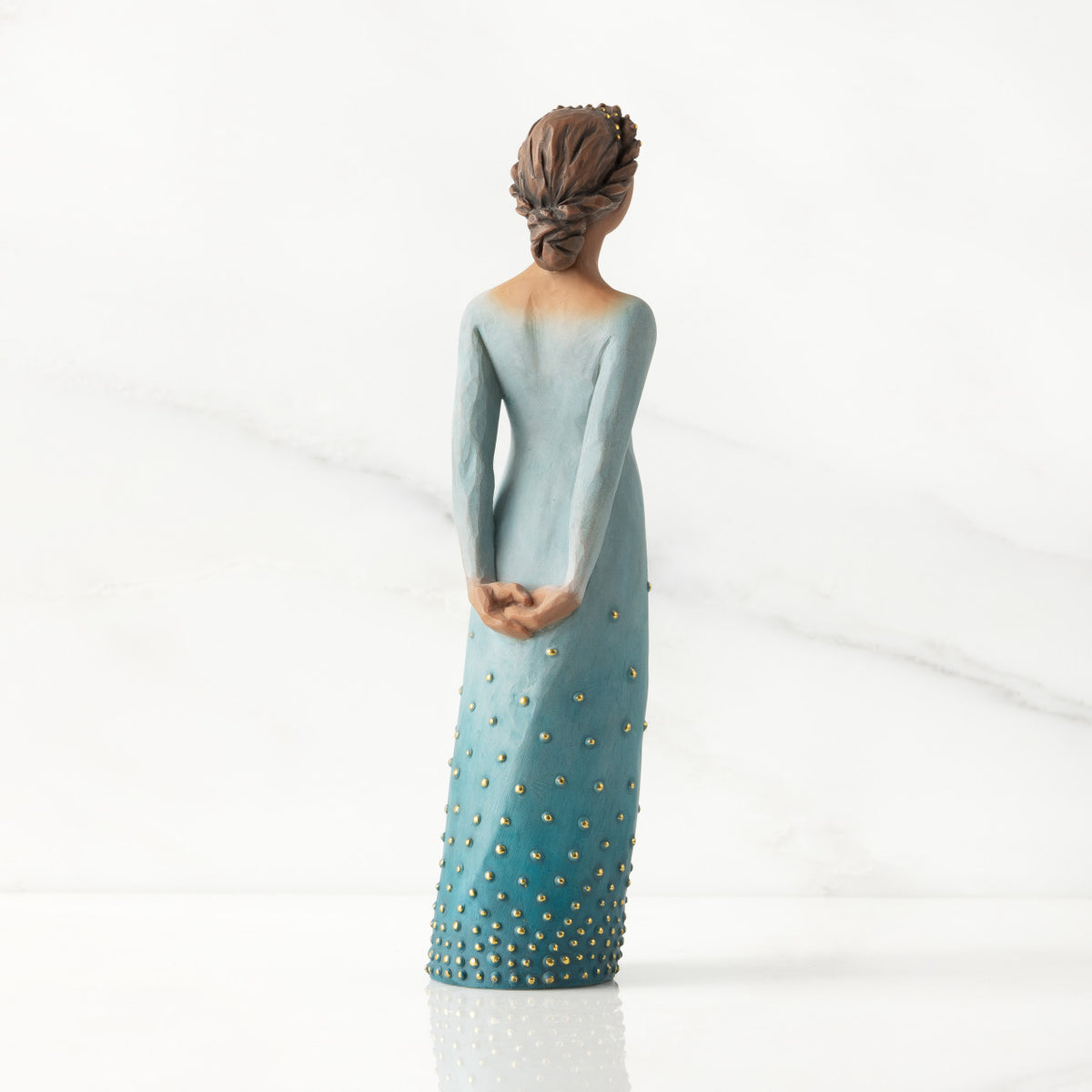 Facing back/right: Darker-skin figure, arms clasped behind back, hair and deep blue ombré garment dotted with gold leaf