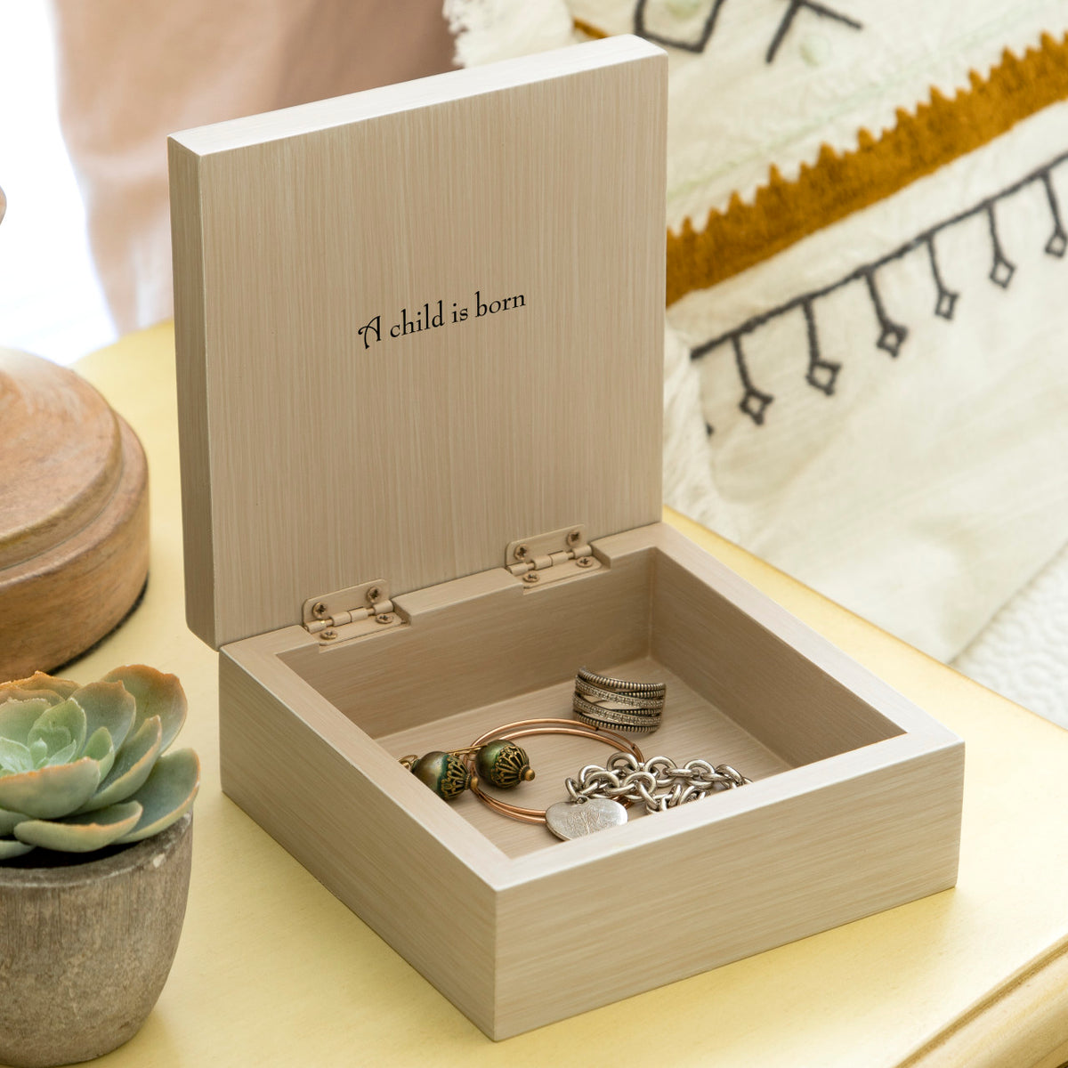 Willow Tree Holy Family Memory Box, 4.75”sq x 2.5”h hand-painted cream wood box, open hinged lid has bas-relief metal-edged carving of the Holy Family affixed to top and ‘A child is born’ sentiment inside