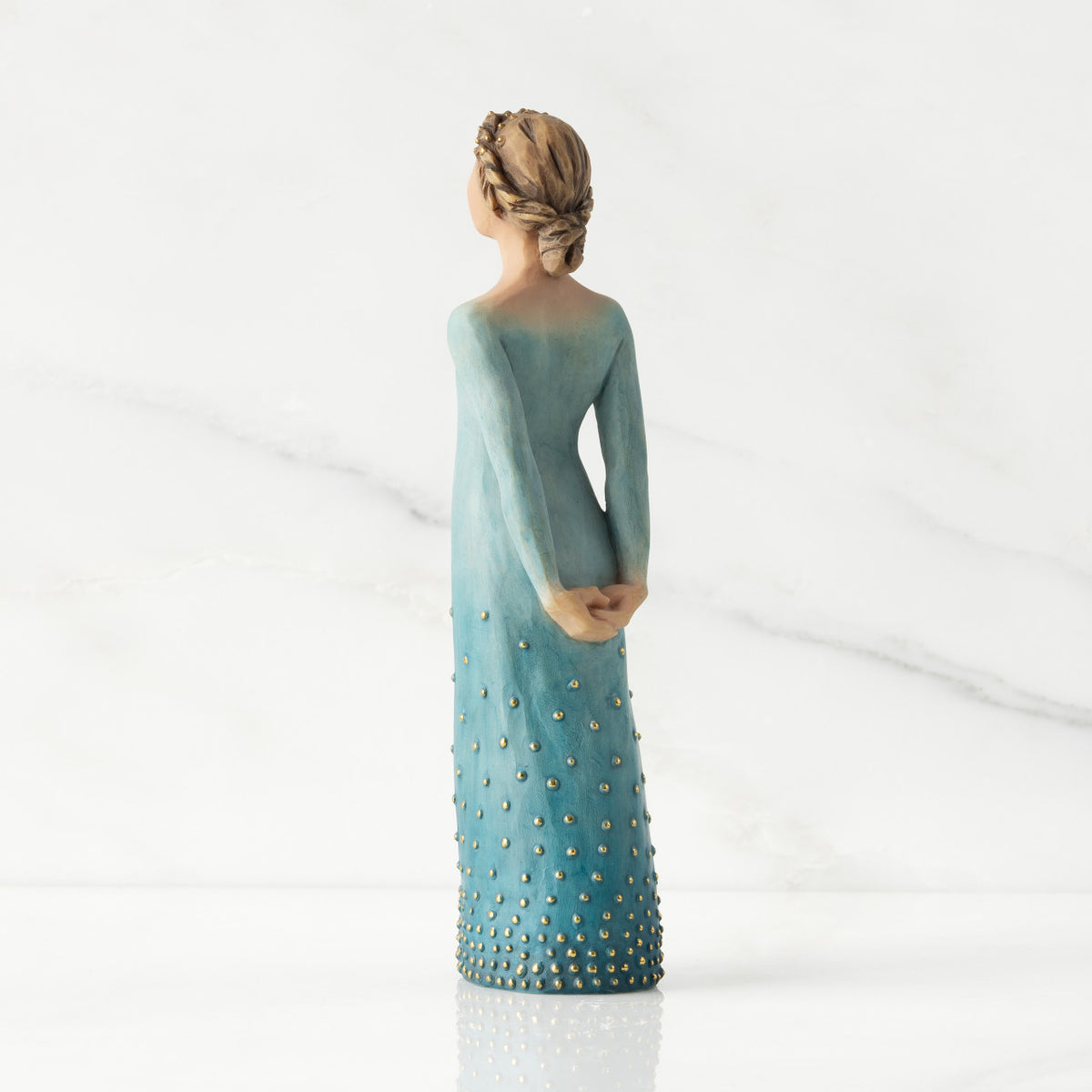 Facing left/back view: Lighter-skin figure, arms clasped behind back, hair and deep blue ombré garment dotted with gold leaf