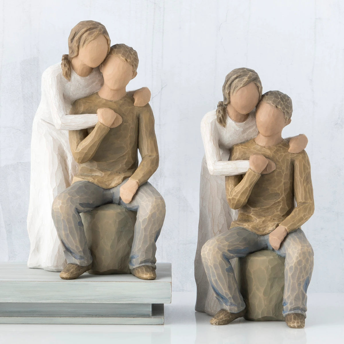Set of two man and woman figurines sitting down with woman's arms on the man