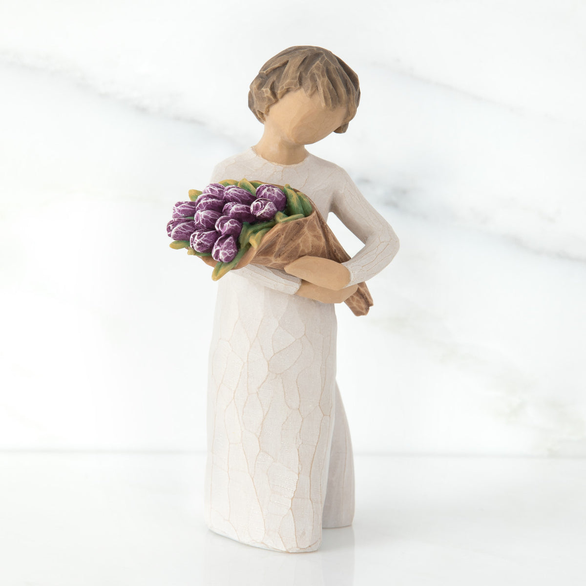 Girl figurine with short brown hair in white dress holding purple flowers