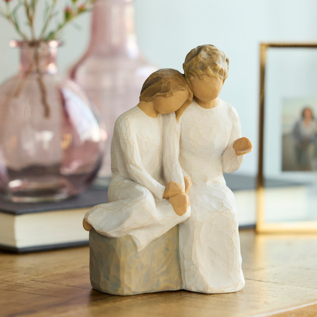 Willow Tree With my Grandmother, 5.5" hand-painted resin figure of older woman seated on gray bench, holding hands with young girl, both in cream dresses, on table with vase