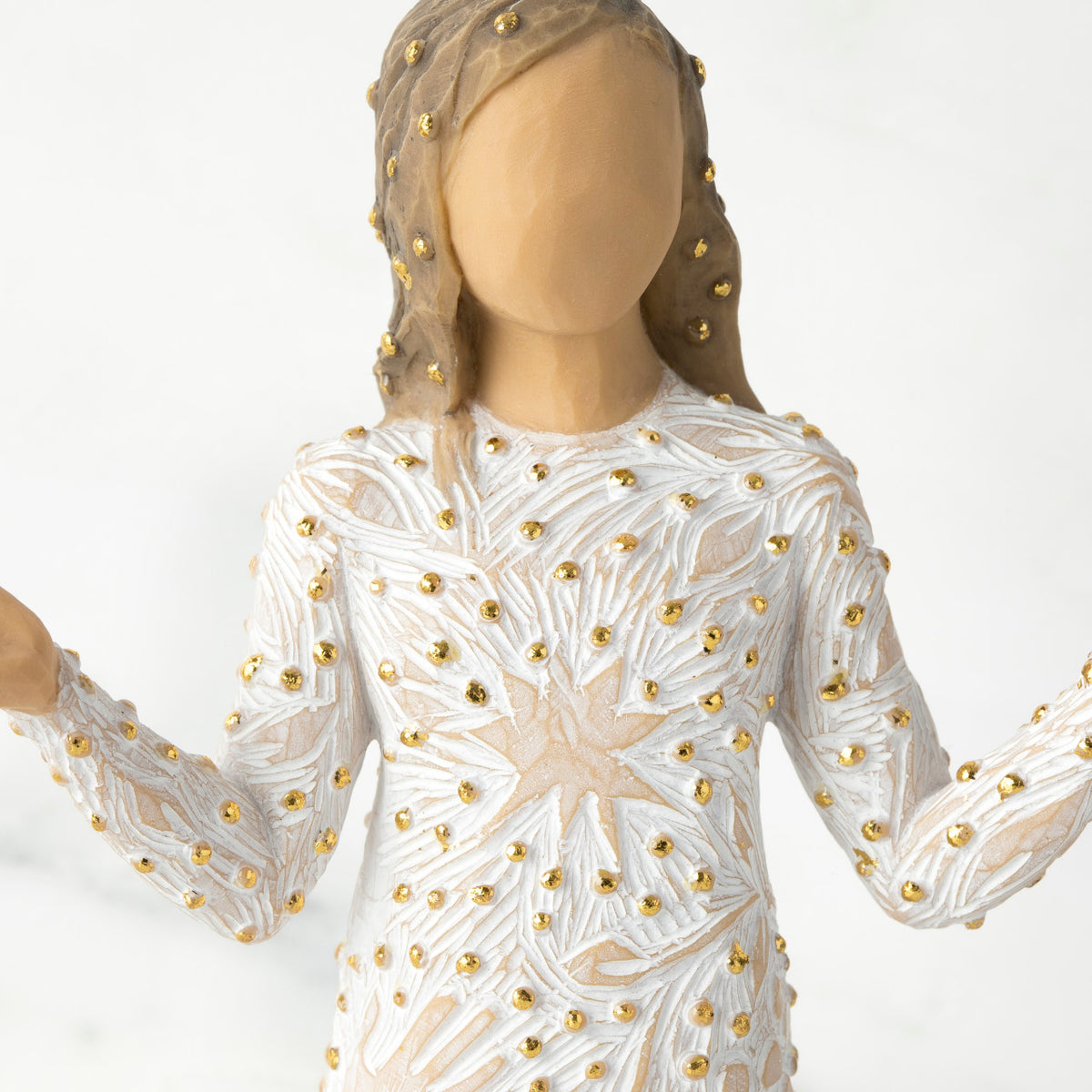 Close view - waist up - of faceless brunette figurine in white dress with gold dots on it
