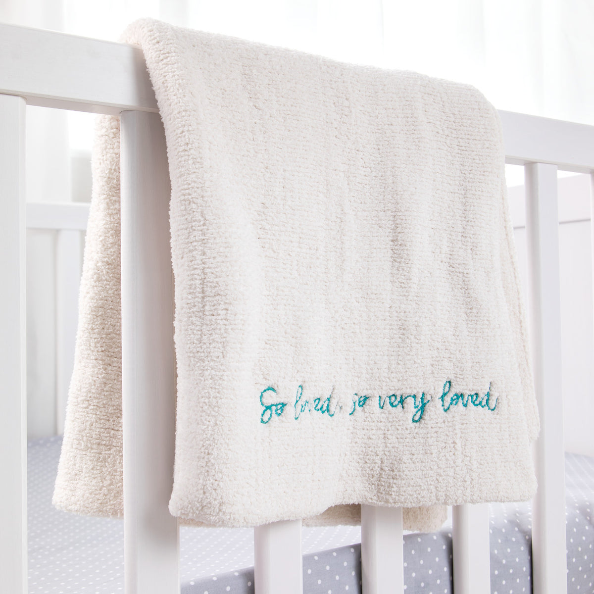 Close view of white towel with 'so loved, so very loved' in blue