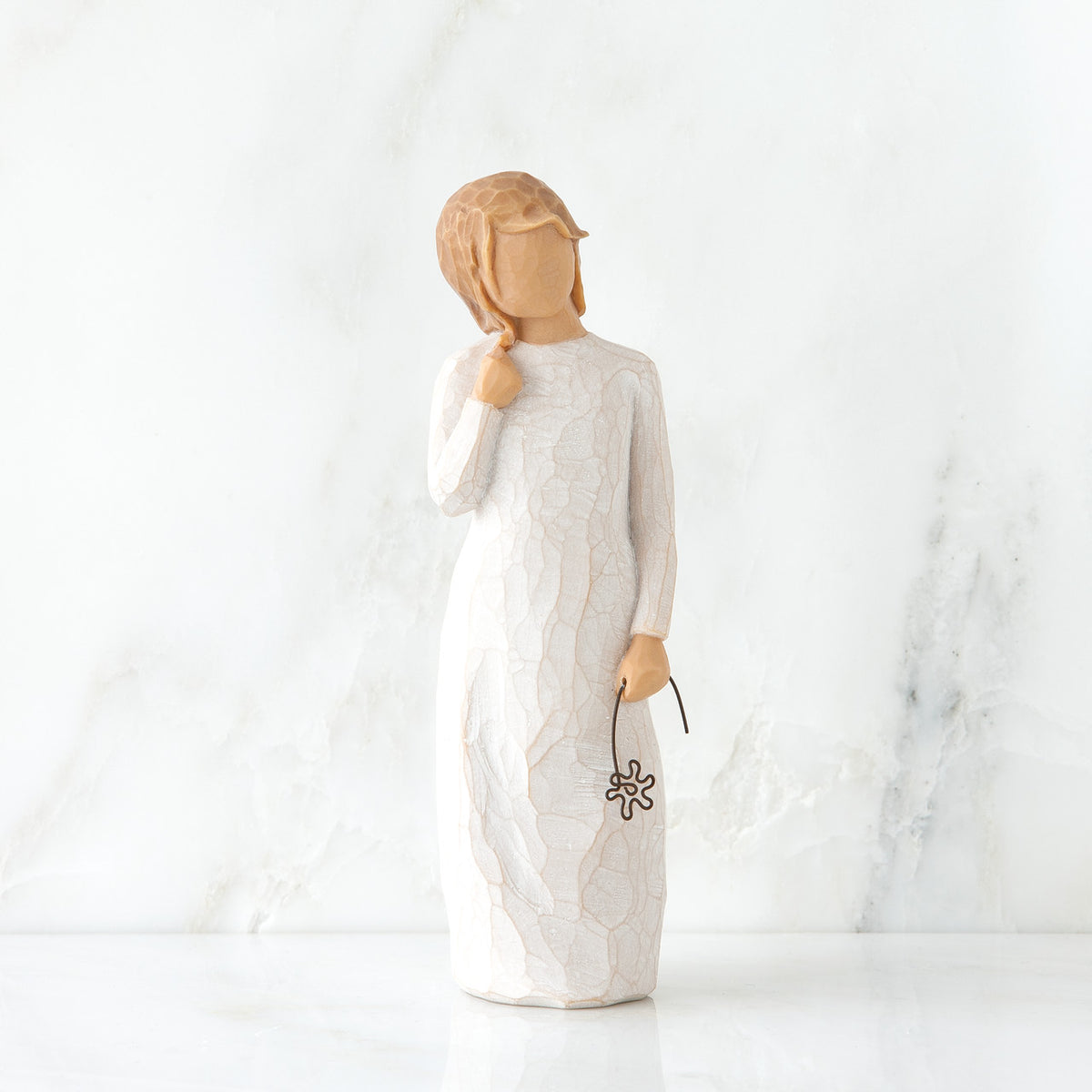 Young blonde girl figurine standing up wearing white dress and holding brown wire flower