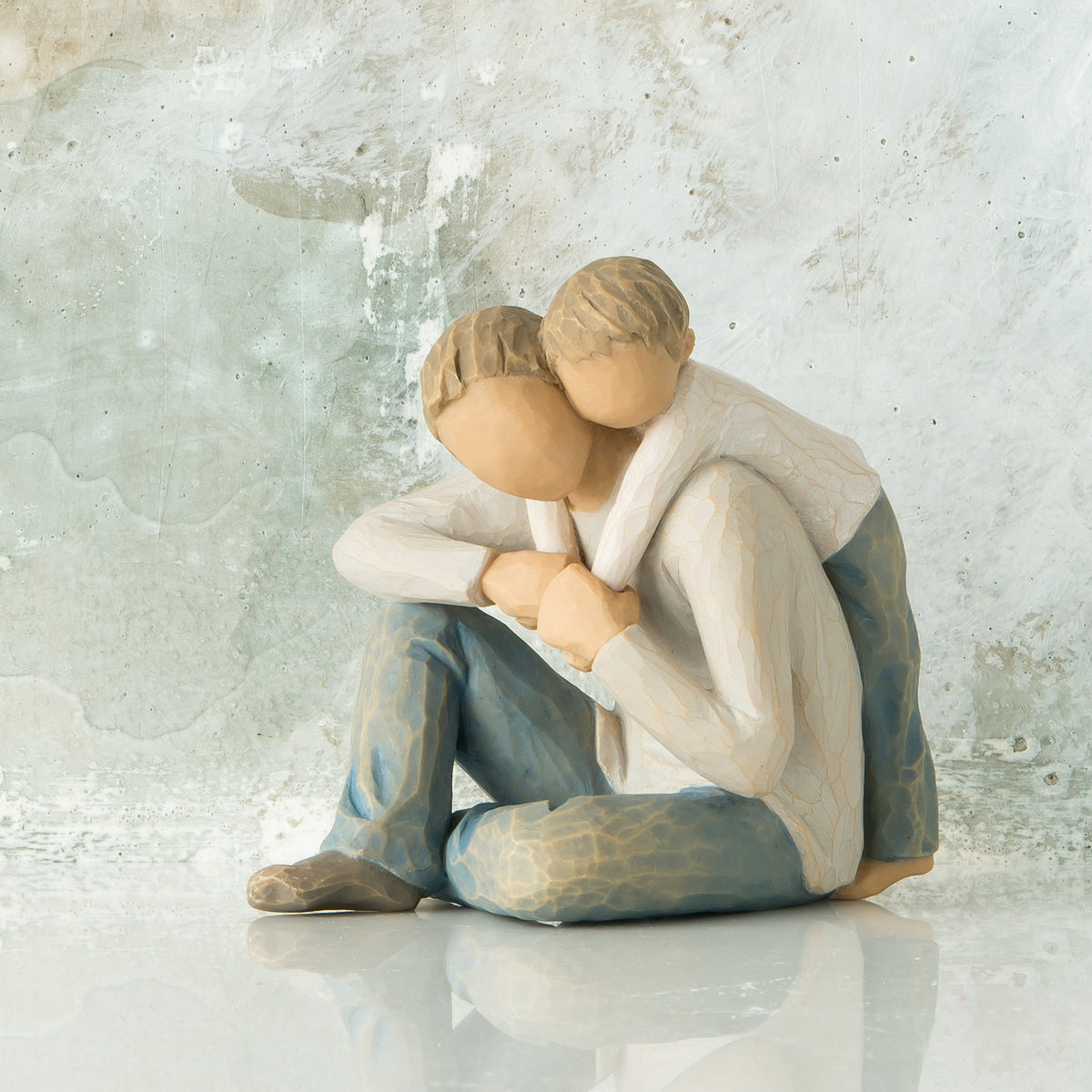Willow Tree That's my Dad, 4”h hand-painted resin figure of seated man with younger boy leaning over his back, both in neutral clothes, in front of light grey painting