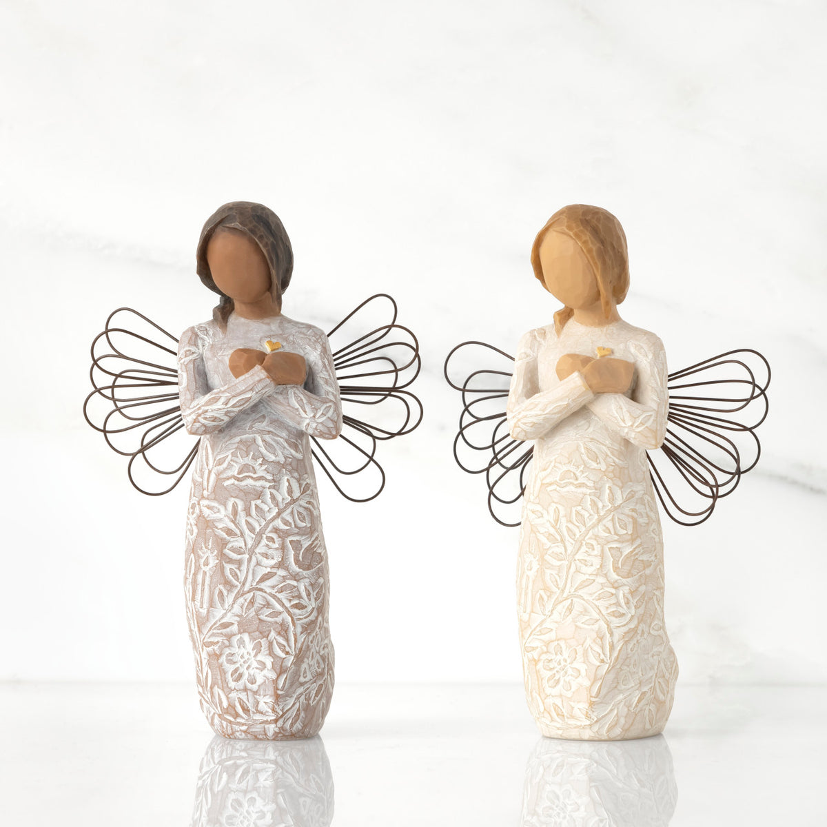 Lighter & Darker skin versions of angel with wire wings, arms crossed over gold heart, carved with symbols of remembrance