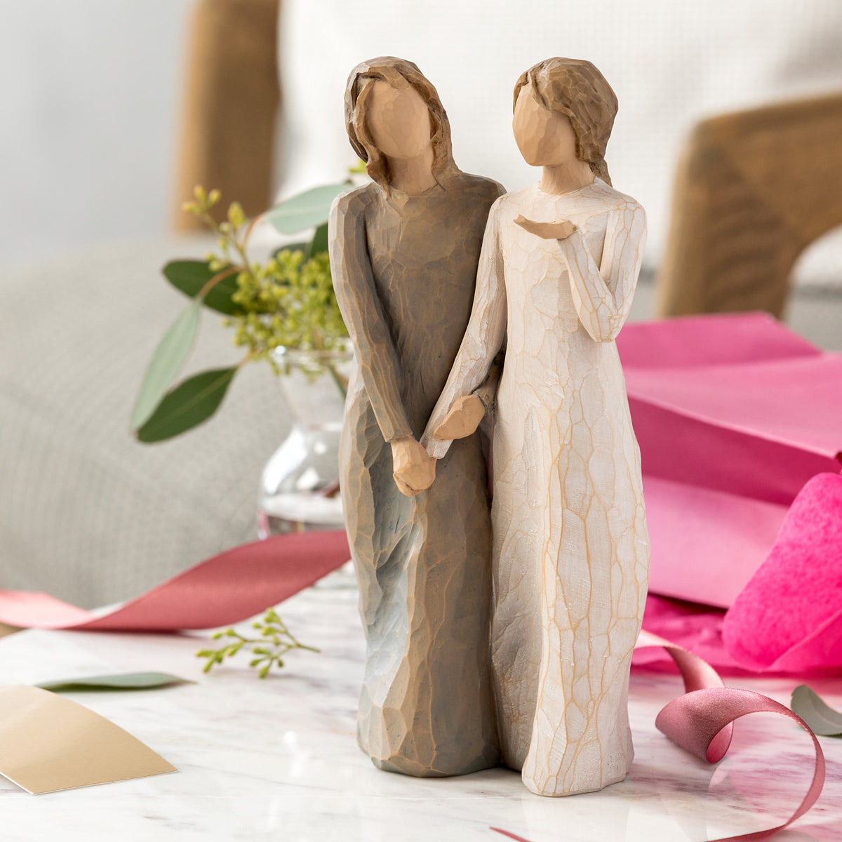 Willow Tree My sister, my friend, 8.5”h hand-painted figure of two females standing next to each other, arms/ hands connected, one in cream dress, one in blue/gray dress, on table with giftwrap