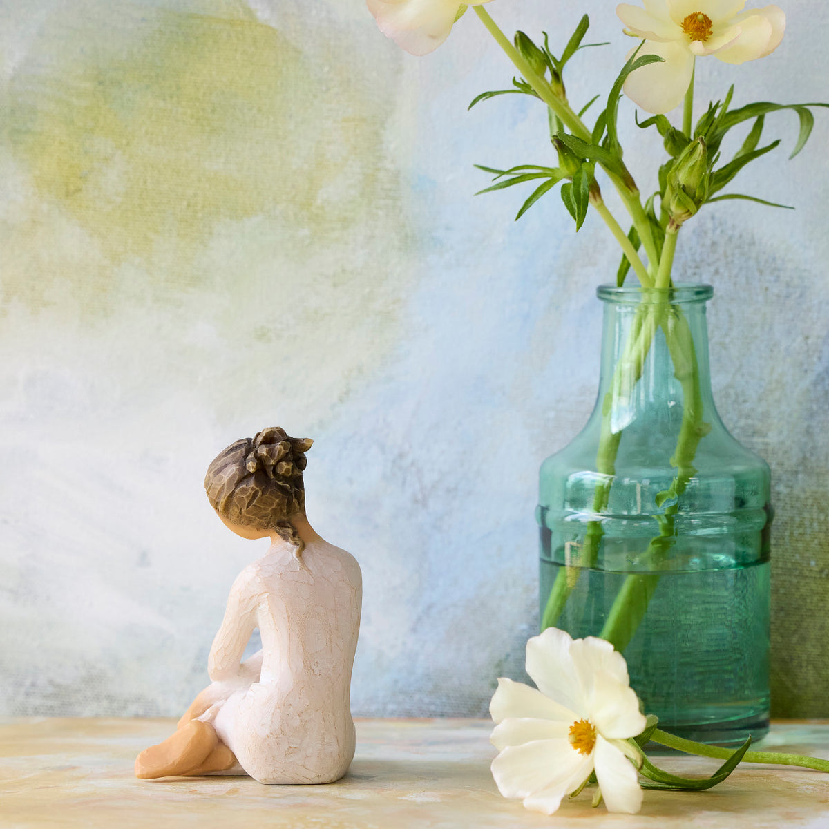Willow Tree Serenity, back view of 3.5”h hand-painted seated figure in cream dress, arms crossed in balletic pose, in front of light blue painting