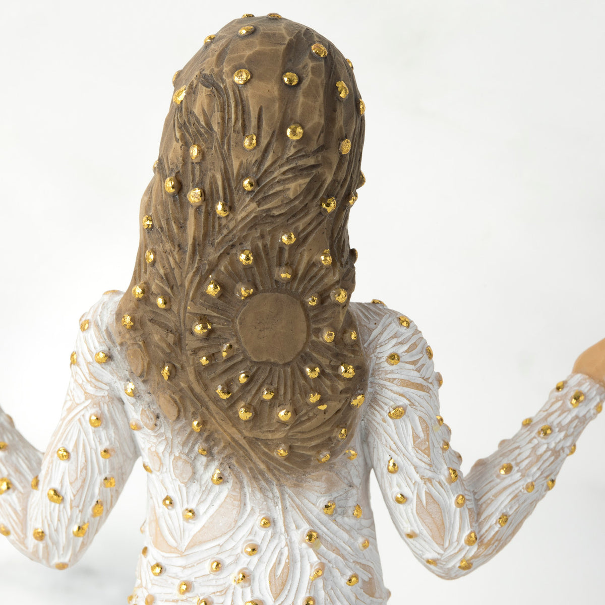 Close view of back of brunette girl figurine in white dress with gold dots