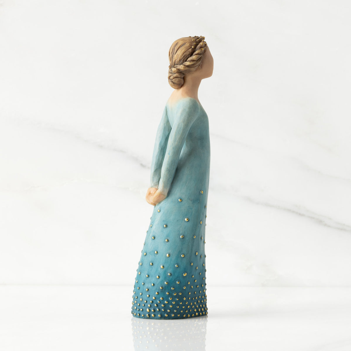 Facing right profile: Lighter-skin figure, arms clasped behind back, hair and deep blue ombré garment dotted with gold leaf