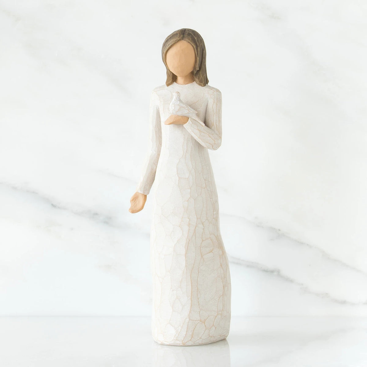 Woman figurine with brown hair in white dress holding white dove