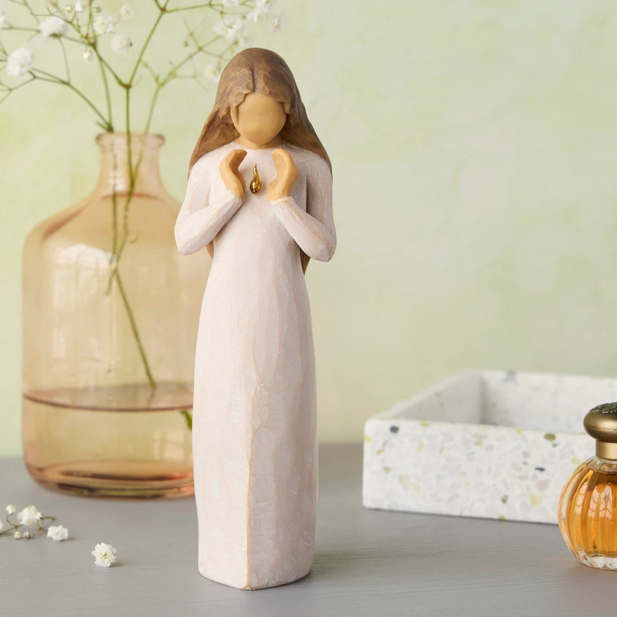 Willow Tree Ever Remember, 7”h hand-painted standing resin figure in cream dress, hands surrounding small gold-leaf flame on chest, on desk with mementos