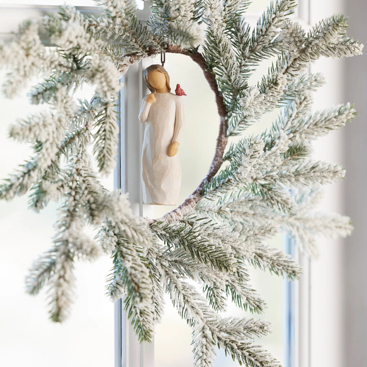 Willow Tree Messenger Ornament, 4”h hand-painted resin figure in cream dress with red cardinal on shoulder, brown elastic cord, hanging inside winter wreath