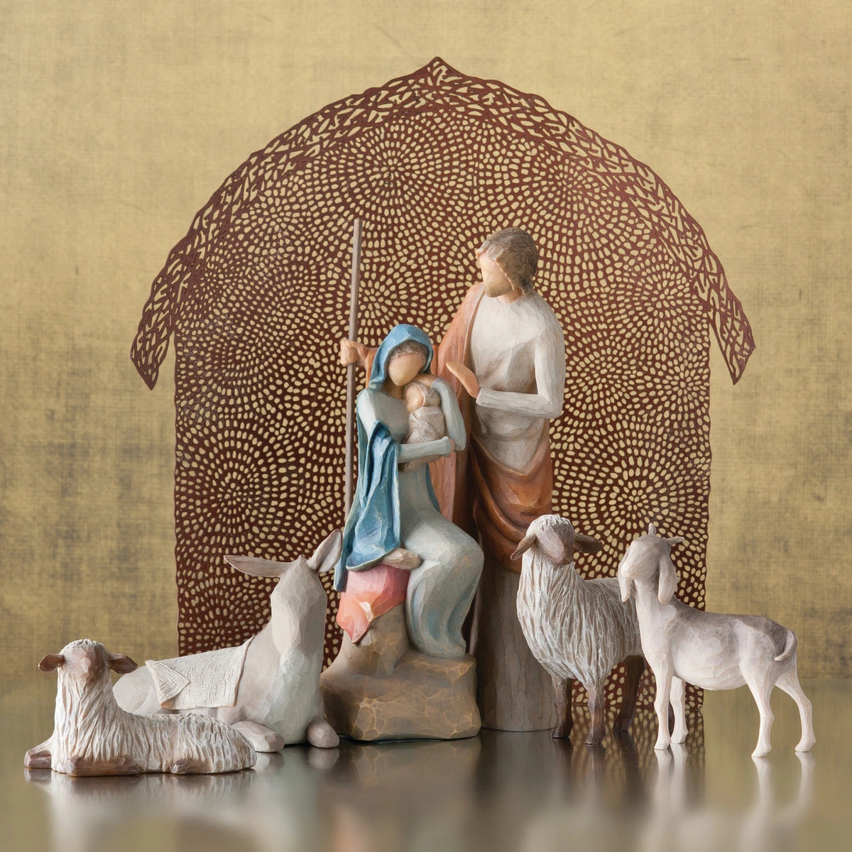 Mary and joesph figurines holding baby with four sheep figurines around them - brown sheer barn paper behind them