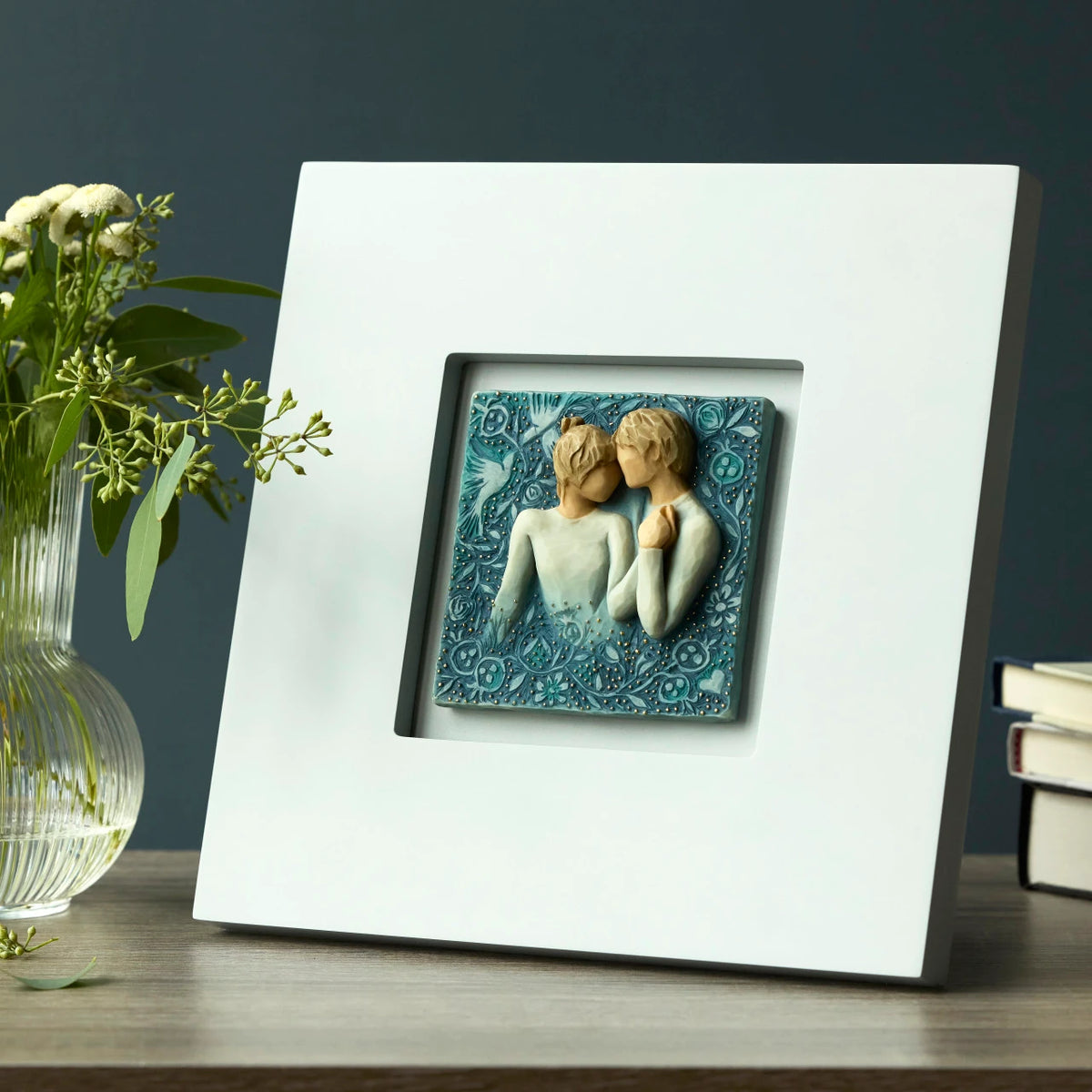 Willow Tree Duet, 10”sq hand-painted dove gray wood frame, with inset bas-relief resin plaque of embracing couple, surrounded by nature, blue ombré background with gold leaf, sitting on table